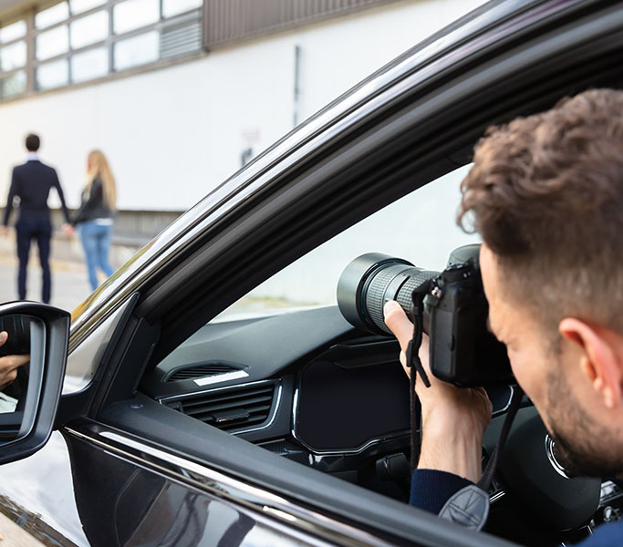 A male in a car taking a picture of a man and a women in the distance